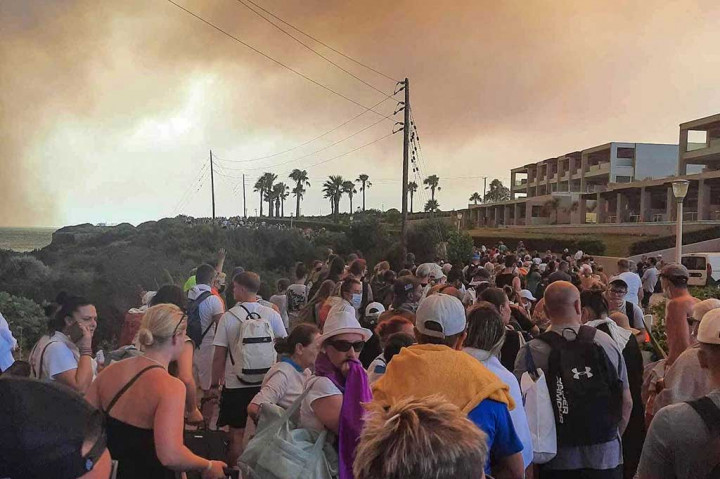 Turis menunggu untuk dievakuasi dari hotel saat kebakaran hutan di Pulau Rhodes Yunani, kemarin. Kebakaran hutan yang melanda Pulau Rhodes selama enam Hari membuat belasan ribu orang dan turis harus dievakuasi. Empat kapal penjaga pantai, 20 kapal pribadi dan satu kapal kargo, satu slipper, dan dua perahu karet militer telah terdaftar untuk membantu upaya evakuasi.