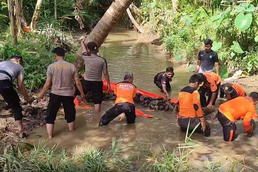 Pengurangan debit aliran sungai Tajur ini dilakukan oleh belasan tim SAR gabungan di bagian hulu sungai sekitar 2 kilometer dari lokasi terjebaknya 8 orang penambang di galian lubang tambang emas, di Desa Pancurendang, Kecamatan Ajibarang, Banyumas, Jawa Tengah, Minggu, 30 Juli 2023. Tim SAR membendung aliran sungai ini dan mengalihkannya ke sungai Datar dengan menggunakan terpal yang ditutup dengan batu.