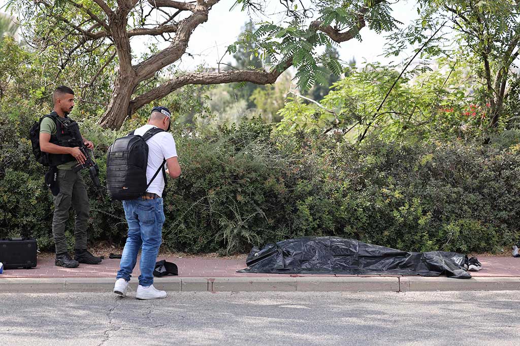 Anggota pasukan keamanan Israel berdiri di dekat jenazah tersangka penyerang di lokasi serangan di pemukiman Israel Maale Adumim di Tepi Barat yang diduduki, Selasa, 1 Agustus 2023.