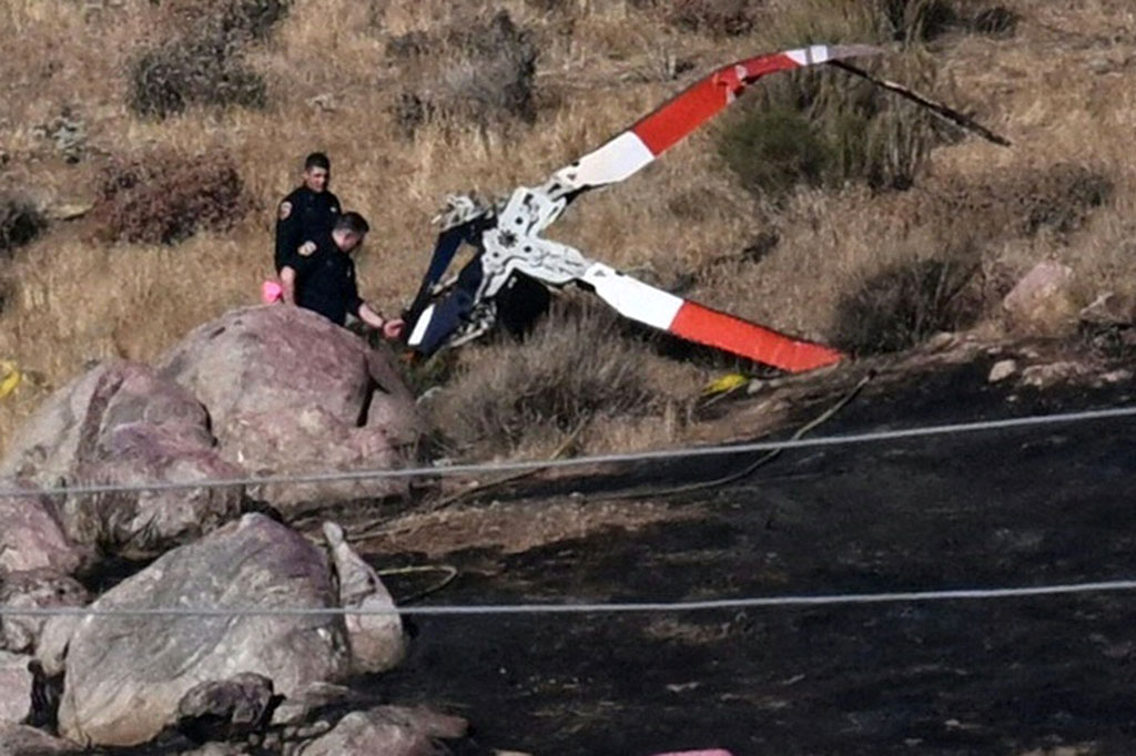 Petugas tengah melakukan penyelidikan di sekitar baling-baling dari salah satu helikopter yang jatuh di lereng bukit yang terbakar di Cabazon, California, Senin, 7 Agustus 2023 waktu setempat.