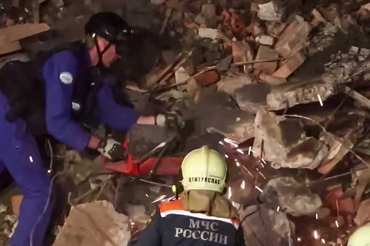 Petugas penyelamat terlihat menggergaji reruntuhan bangunan yang runtuh semalaman, sementara petugas pemadam kebakaran menyemprotkan air ke reruntuhan yang membara. Penyebab insiden itu tidak segera jelas.