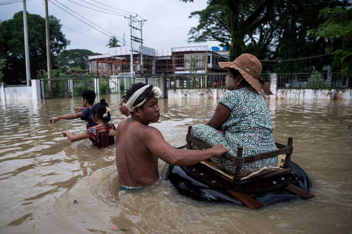 Warga mengarungi banjir setinggi pinggul di sepanjang jalan setelah hujan monsun melanda kotapraja Bago, wilayah Bago, Myanmar, Jumat, 11 Agustus 2023.