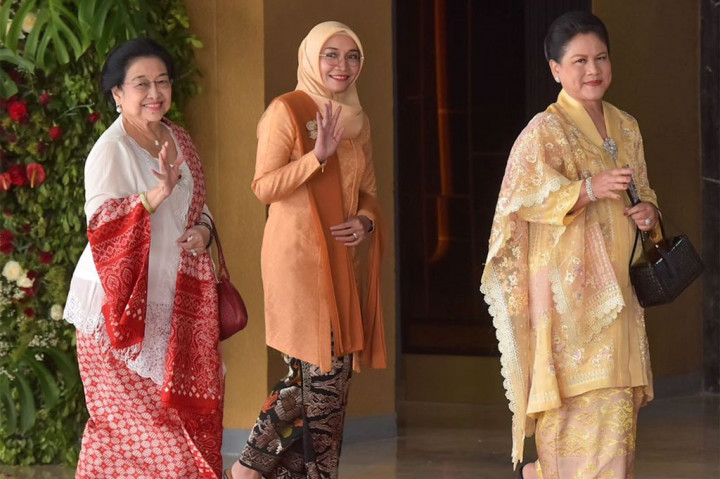 Sementara itu, Ibu Iriana tampak mengenakan setelan busana panjang berwarna emas yang dilengkapi dengan selendang dengan warna senada yang dipasang di pundak kanannya, serta riasan sederhana dan rambut digelung manis. 