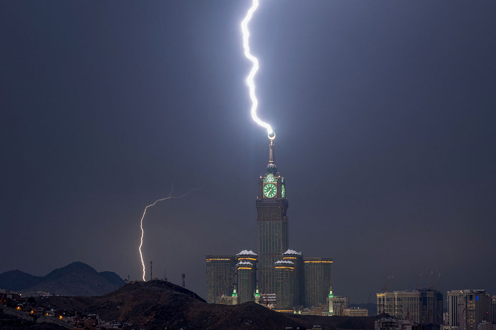 Menghadap Ka'bah yang suci, menara jam terbesar di dunia tersebut diterangi oleh sambaran petir yang cemerlang, menyinari seluruh kota.