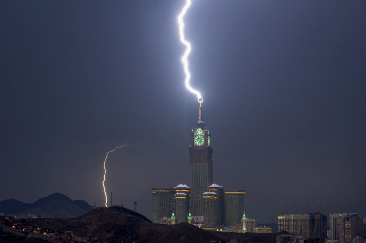Menghadap Ka'bah yang suci, menara jam terbesar di dunia tersebut diterangi oleh sambaran petir yang cemerlang, menyinari seluruh kota.