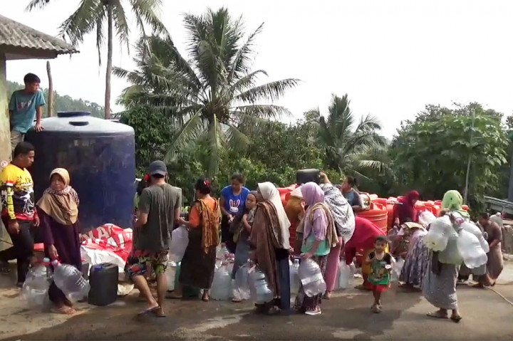 Warga Kampung Tembulun, Kelurahan Mekarsari, Kecamatan Pulomerak, Kota Cilegon, Banten berebut mengisi jeriken yang mereka bawa untuk diisi air bersih bantuan dari Ditreskrimsus Polda Banten dan KNPI Kota Cilegon.