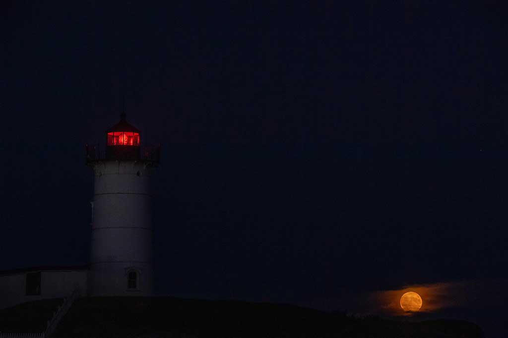 Super Blue Moon muncul di belakang Mercusuar Nubble di Cape Neddick, York, Maine, Amerika Serikat, Rabu, 30 Agustus 2023 waktu setempat. AFP PHOTO/Joseph Prezioso