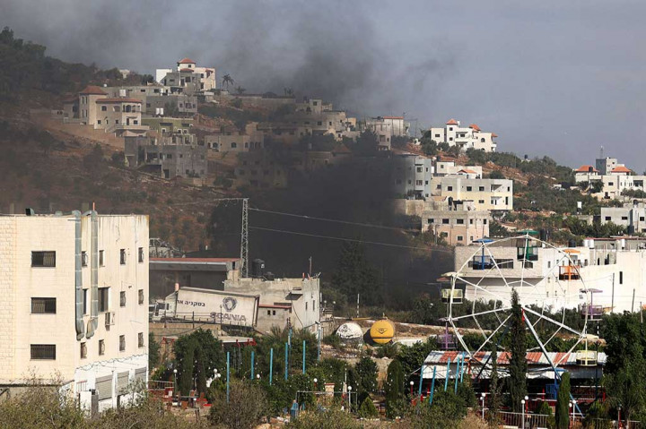 Seorang fotografer AFP melihat asap hitam mengepul dari sebuah gedung selama serangan militer. 