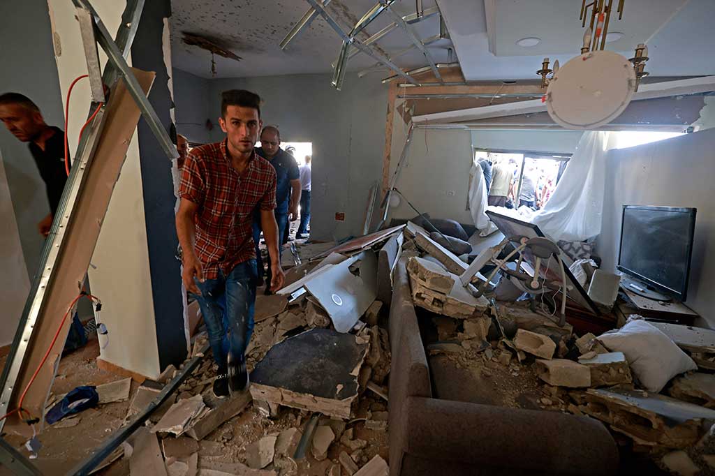 Setelah pasukan Israel mundur, warga Palestina memeriksa bekas peluru dan lubang menganga yang tertinggal di dinding sebuah rumah.