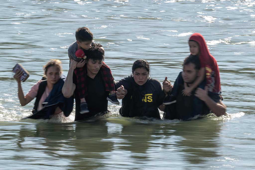 Sebuah keluarga mengarungi arus deras di Sungai Rio Grande saat mereka melintasi perbatasan AS-Meksiko menuju Eagle Pass, Texas pada Sabtu, 23 September 2023.