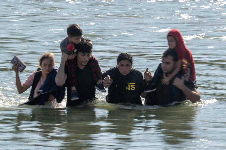 Sebuah keluarga mengarungi arus deras di Sungai Rio Grande saat mereka melintasi perbatasan AS-Meksiko menuju Eagle Pass, Texas pada Sabtu, 23 September 2023.