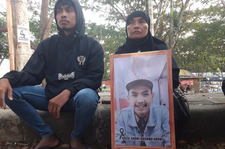 Ibu Yuliati duduk sembari memegang foto mendiang putranya di trotoar luar Stadion Kanjuruhan, Kabupaten Malang, Jawa Timur. Sang putra adalah Bregi Andri Kusuma Anggi, anak kedua dari empat bersaudara.
