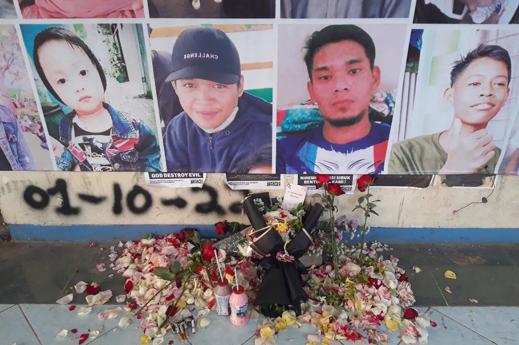 Yuliati memilih duduk tepat di depan pintu seperti menunggu kedatangan sang anak. Matanya menerawang, ia terus memandangi pintu keluar 13 yang tak jauh dengan pintu utama D stadion berkapasitas 30 ribu penonton
tersebut. Mulut sang ibu tercekat. Di pintu itu terlihat foto-foto 135 korban Tragedi Kanjuruhan dan bunga tabur.