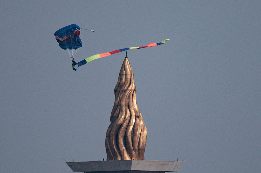 Dari videotron yang ada di lokasi perayaan, satu per satu personel terjun bebas dari sebuah pesawat yang terbang di langit Ibu Kota. Begitu mendekati Monas, puluhan peterjun ini membuka parasut masing-masing.