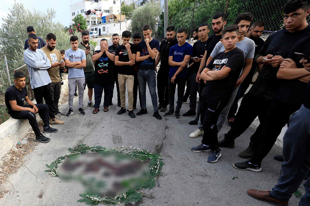 Warga berkumpul di sekitar noda darah yang dikelilingi dedaunan dekat kota Tulkarem di Tepi Barat, tempat dua warga Palestina dilaporkan tewas dalam bentrokan dengan pasukan Israel pada Kamis, 5 Oktober 2023.