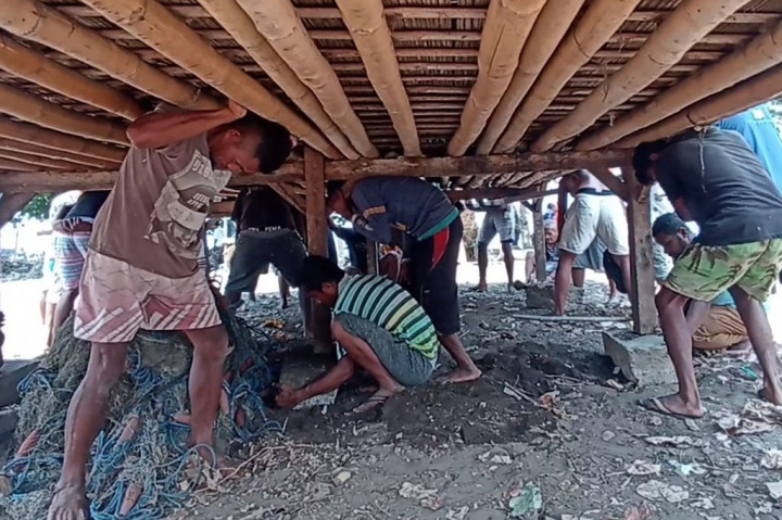 Di bawah komando salah satu warga yang berdiri di tiang depan, warga tua dan muda, pria dan wanita, secara bergotong royong dan serentak mengangkat dan menggotong rumah tersebut menuju lokasi baru.