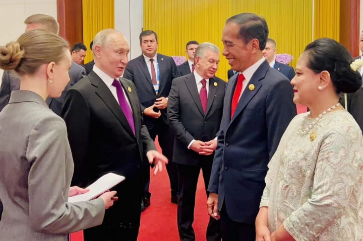 Terlihat Jokowi mengenakan jas berwarna biru dongker dengan dasi berwarna merah, Iriana mengenakan kebaya berwarna krem, sedangkan Vladimir Putin mengenakan jas berwarna hitam dengan dasi ungu.