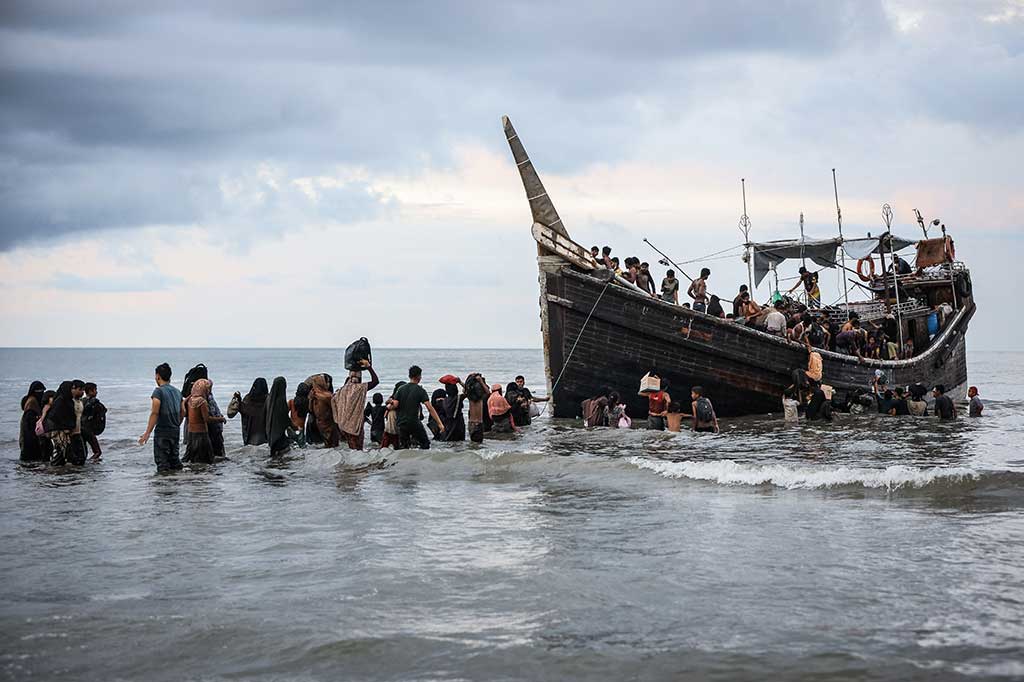 Pria, wanita, anak-anak, dan bayi terlihat melihat ke pantai ketika penduduk setempat yang marah meminta mereka untuk tidak mendaratkan kapal tersebut, yang menurut beberapa penumpang kapal berlayar dari Bangladesh.