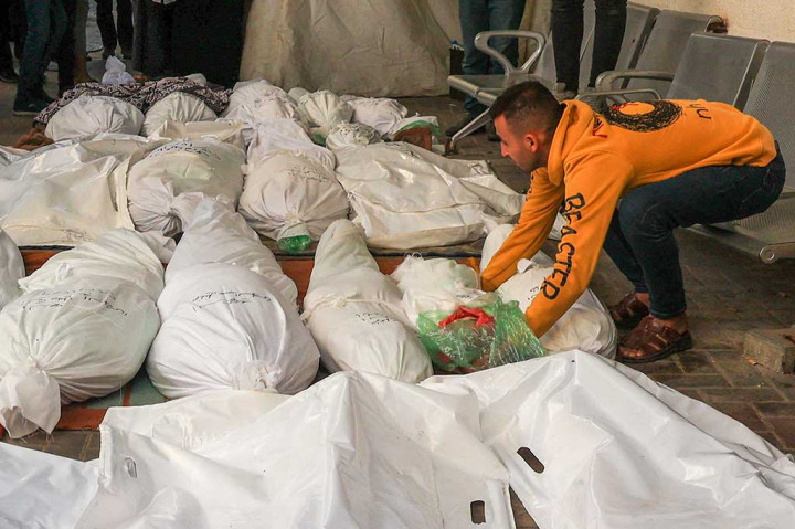 Seorang pria meletakkan jenazah anaknya yang berusia dua tahun, yang terbunuh bersama beberapa korban lainnya selama pemboman Israel semalam, di luar Rumah Sakit al-Najjar di Rafah, Jalur Gaza selatan, Kamis, 7 Desember 2023.