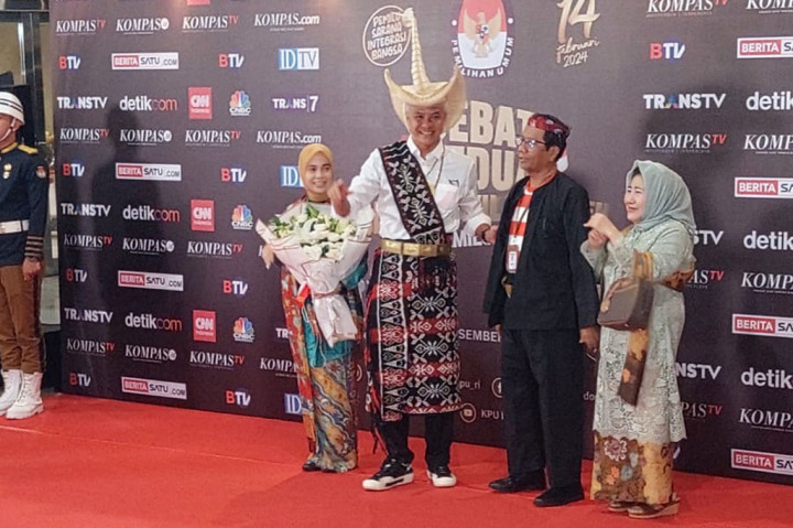 Ganjar tampak mengenakan pakaian adat Nusa Tenggara Timur (NTT) berupa kain tenun yang dibentuk selimut ikat. Ia juga lengkap mengenakan topi adat tersebut.