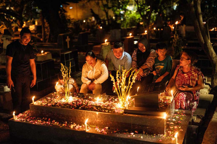 Sejumlah warga menggelar tradisi nyekar dengan menyalakan lilin dan menaburkan bunga di Pemakaman Gereja Tugu yang berlokasi di Kelurahan Sempet Barat, Cilincing, Jakarta Utara, Minggu, 24 Desember 2023.