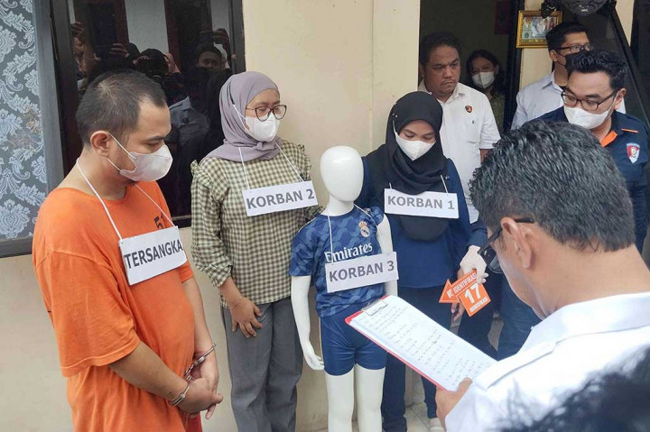 Tampak Panca yang mengenakan pakaian tahanan berwarna oranye hanya menundukkan kepalanya saja saat berjalan. Dia juga dikalungi sebuah alat peraga bertuliskan tersangka di bagian bawah lehernya.