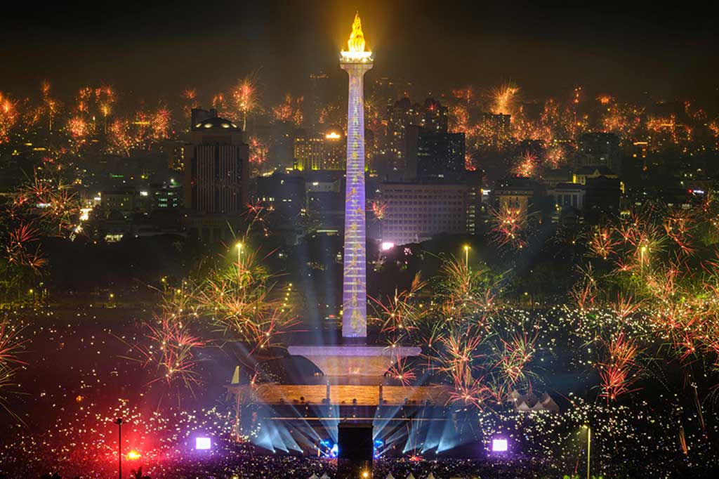 Pengunjung terlihat antusias mengambil foto dan video saat kembang api menghiasi langit di Monas.