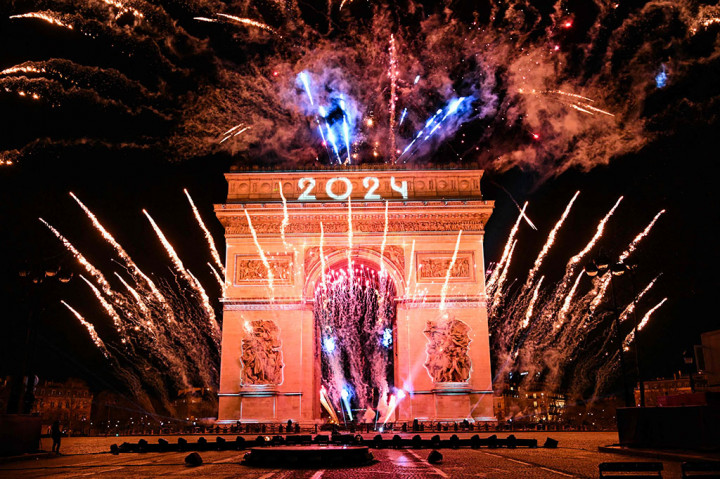 Kembang api meledak di sebelah Arc de Triomphe dengan proyeksi 2024, di Avenue des Champs-Elysees saat perayaan Tahun Baru di Paris, awal 1 Januari 2024. 