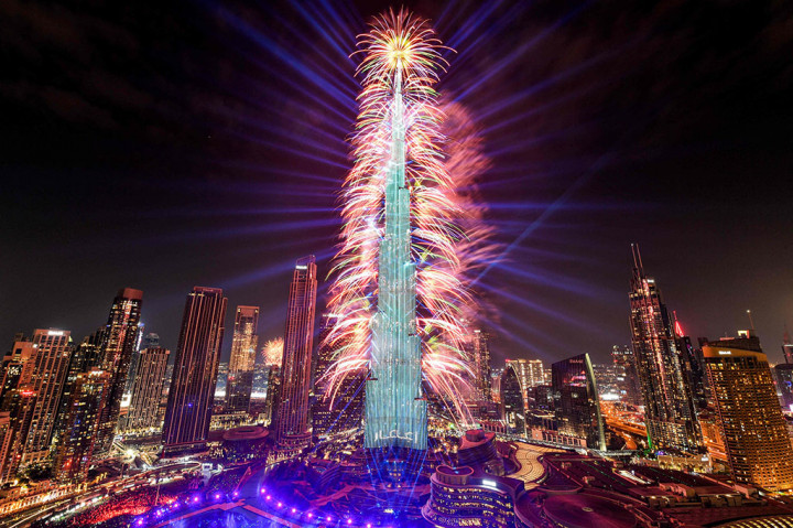 Kembang api menerangi langit di dekat gedung pencakar langit Burj Khalifa, gedung tertinggi di dunia, di Dubai pada tengah malam malam tahun baru pada 1 Januari 2024. 