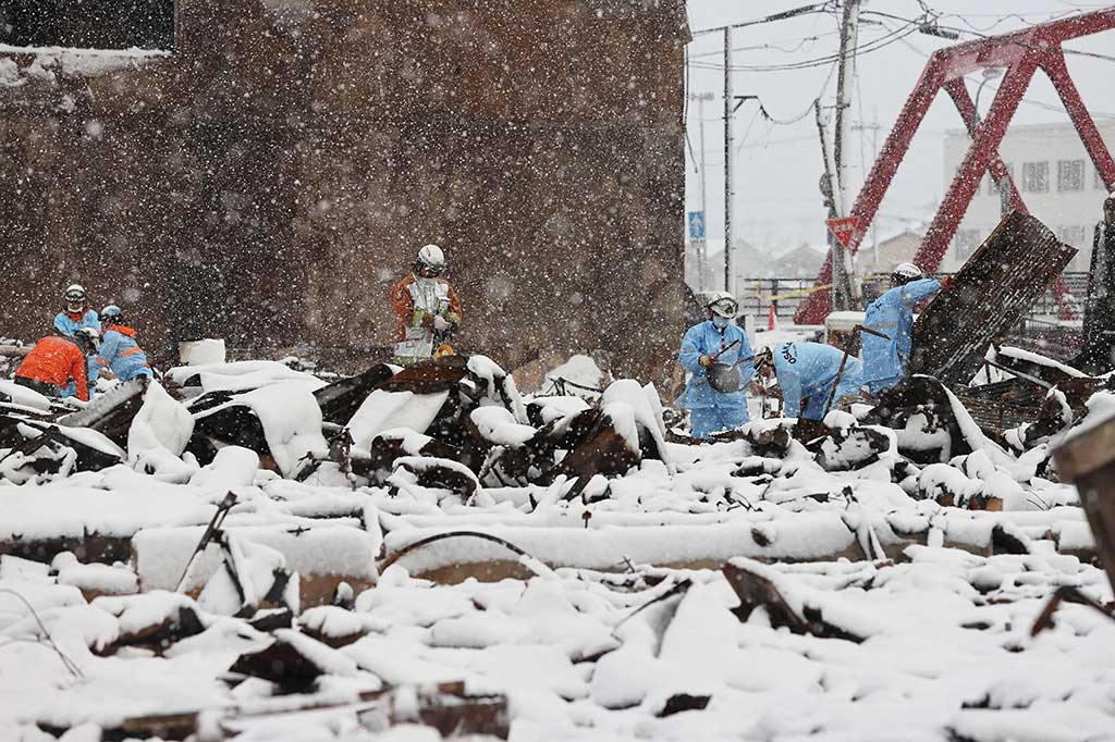 Petugas pemadam kebakaran mencari orang hilang di reruntuhan Pasar Wajima yang terbakar saat salju menyelimuti sebagian daerah yang terkena bencana di Kota Wajima, Prefektur Ishikawa, Senin, 8 Januari 2024.