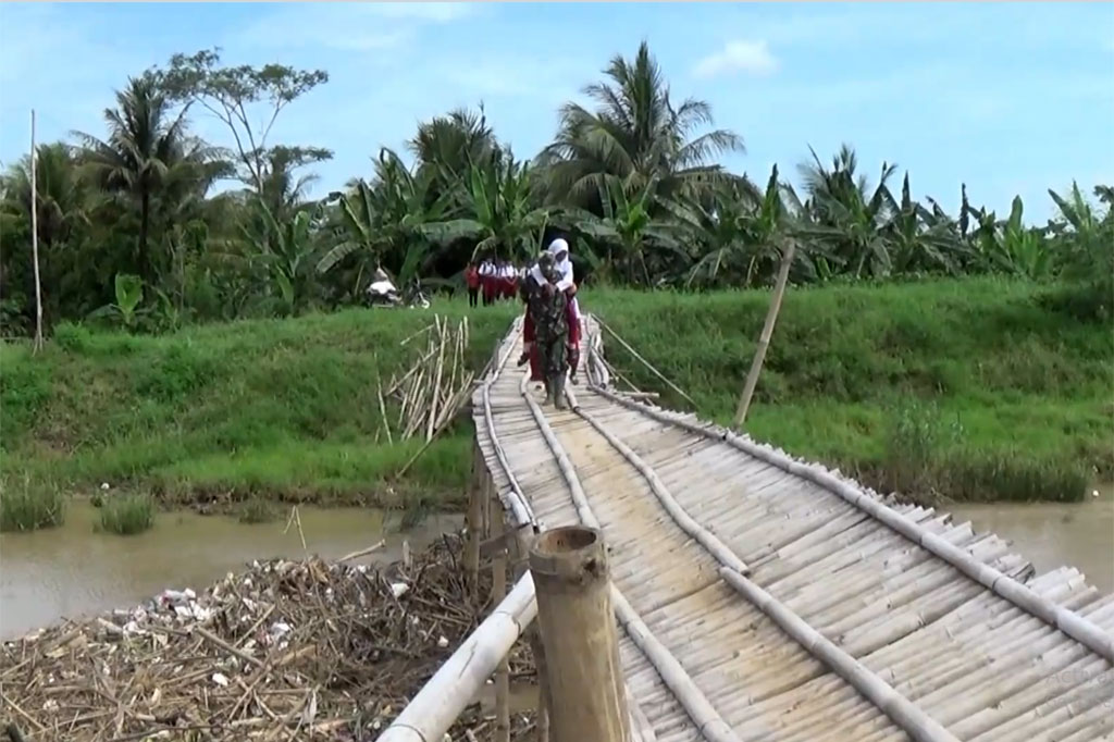 Sebuah jembatan bambu yang biasa digunakan warga di wilayah Kecamatan Kampung Laut, Cilacap, Jawa Tengah nyaris ambruk setelah tiang penyangganya dipenuhi tumpukan sampah. Ironisnya, para siswa tetap nekat menggunakannya untuk menyebrang meski harus menantang bahaya karena kondisi jembatan yang telah miring.