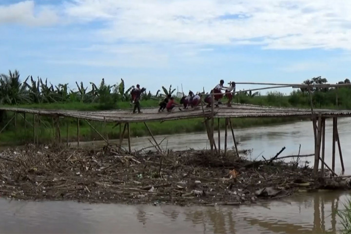Sebelumnya, sejak satu pekan terakhir, wilayah ini sering dilanda hujan dan membuat banyak sampah yang tersangkut di tiang jembatan. Akibatnya, tiang jembatan yang juga terbuat dari bambu tidak kuat menahan beban dan menjadi miring. Lantai jembatanpun akhirnya miring dan rusak, padahal ini merupakan satu-satunya akses terdekat warga. 