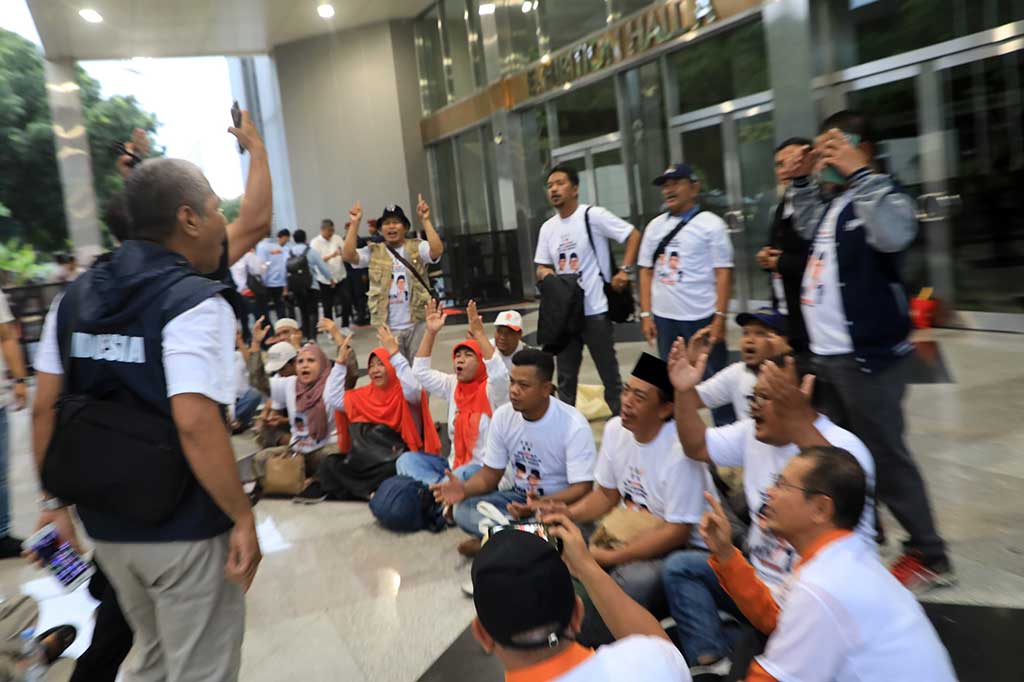 Para pendukung yang mengenakan seragam putih tersebut duduk bersila di depan Exhibition Hall A, tepat di samping pendukung pasangan calon (paslon) capres-cawapres nomor urut 2, Prabowo Subianto-Gibran Raka Buming Raka.