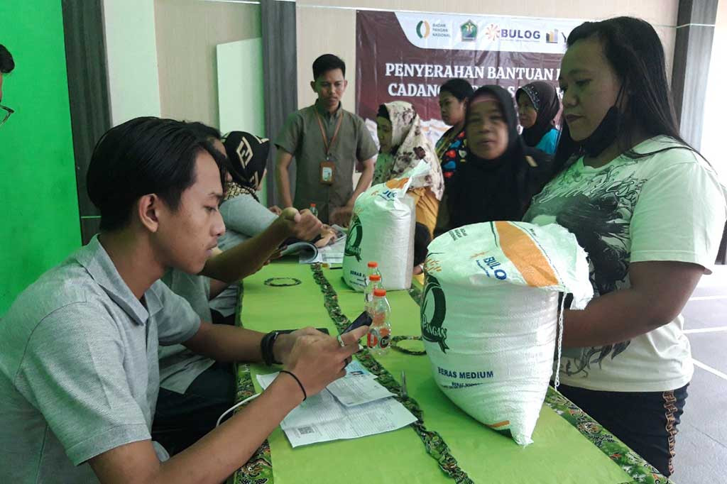 Ibu Musyarofah sembari menggendong sang buah hati berusia dua tahun antre sejak pagi hari bersama warga lainnya di Kantor Kelurahan Buring, Kecamatan Kedungkandang, Kota Malang, Jawa Timur, Kamis, 1 Februari 2024. Orang tua tunggal itu bergegas mengambil beras medium bulog bantuan pangan wadah karung isi 10 kg usai dipanggil petugas melalui pengeras suara. Satu per satu warga tertib menerima bantuan.