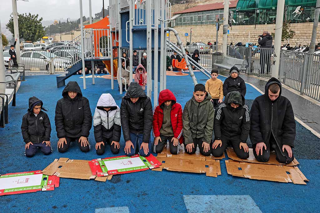 Muslim Palestina melaksanakan salat Jumat dengan sajadah memakai kardus di area bermain di jalan yang diblokir oleh pasukan keamanan Israel di lingkungan Ras al-Amud di Yerusalem timur, Jumat, 2 Februari 2024.