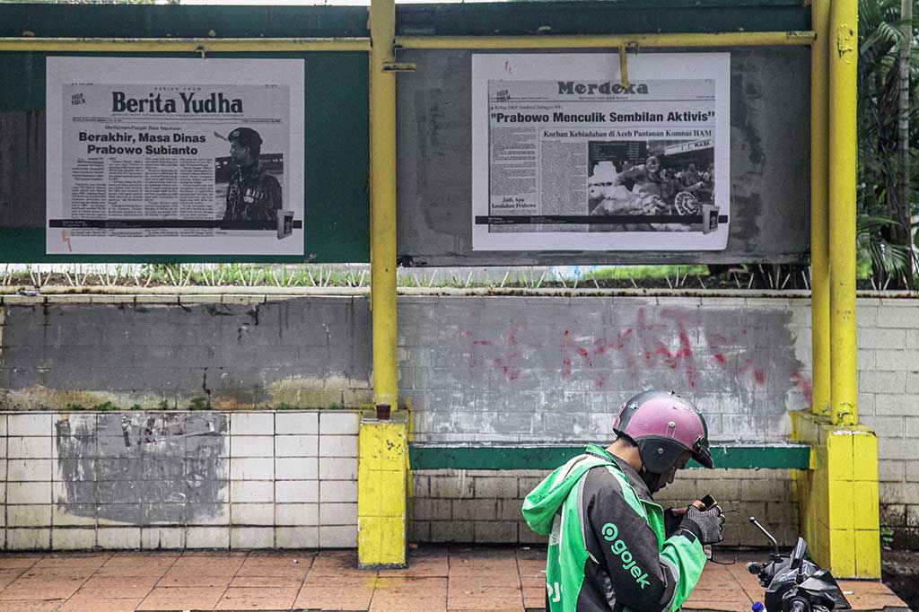 engojek online berada di depan fotokopi kliping koran tahun 98 terkait kasus pelanggaran HAM berat yang dipasang di jalur pedestrian, Jalan Rasuna Said, Jakarta, Selasa, 6 Februari 2024.