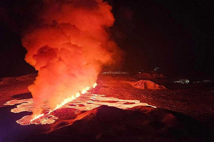 Gambar video menunjukkan lava bercahaya keluar dari celah yang menyinari kepulan asap yang membubung di bawah langit malam.