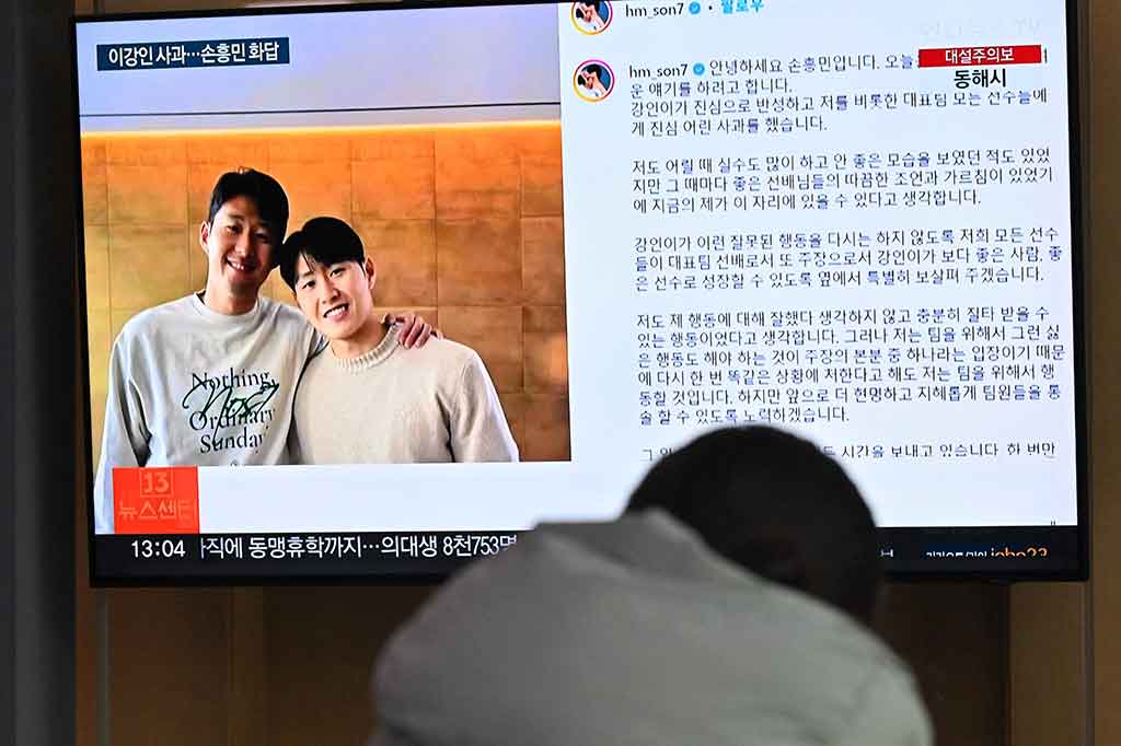 Seorang wanita menonton layar televisi yang menayangkan siaran berita bergambar Son Heung-min (kiri) dan Lee Kang-in (kanan), di stasiun kereta api di Seoul, Korea Selatan, Rabu, 21 Februari 2024. Son Heung-min meminta maaf atas perannya dalam perselisihan dengan rekan setimnya di  timnas Korea Selatan Lee Kang-in pada Piala Asia 2023.