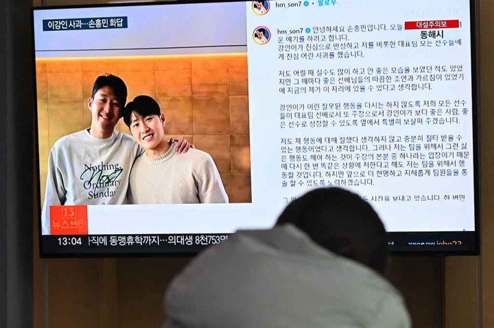 Seorang wanita menonton layar televisi yang menayangkan siaran berita bergambar Son Heung-min (kiri) dan Lee Kang-in (kanan), di stasiun kereta api di Seoul, Korea Selatan, Rabu, 21 Februari 2024. Son Heung-min meminta maaf atas perannya dalam perselisihan dengan rekan setimnya di  timnas Korea Selatan Lee Kang-in pada Piala Asia 2023.