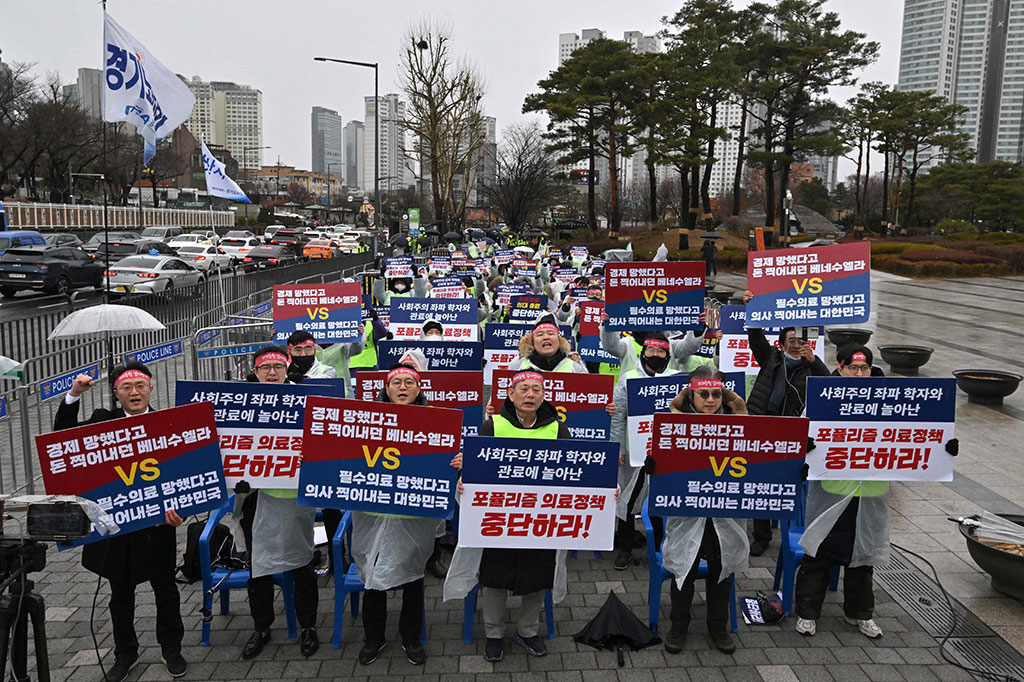 Ratusan dokter memegang plakat bertuliskan 