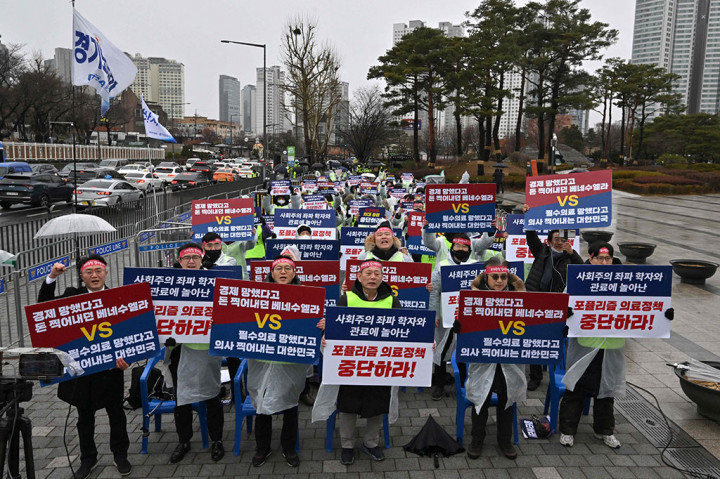 Ratusan dokter memegang plakat bertuliskan 