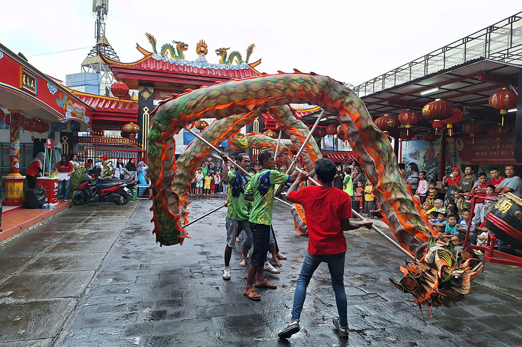 Delapan orang pemain liong menari di bawah guyuran hujan deras pada Pesta Rakyat di halaman Klenteng Hok Tek Bio Purwokerto, Jawa Tengah mulai pukul 16.20 wib, Sabtu, 24 Februari 2024 Sore. Empat penabuh gendang membunyikan musik mengiringi liukan tarian naga khas Tiongkok. 