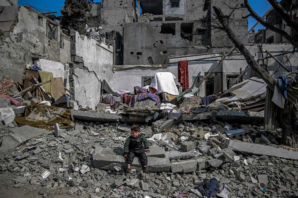 Seorang anak Palestina duduk di tengah puing-puing dekat bangunan yang hancur akibat serangan Israel di Beit Lahia di Jalur Gaza utara, Senin, 26 Februari 2024, di tengah berlanjutnya pertempuran antara Israel dan kelompok militan Palestina Hamas.