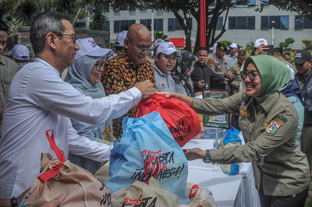 Penjabat (Pj) Gubernur DKI Jakarta Heru Budi Hartono melayani aparatur sipil negara (ASN) dan penyedia jasa lainnya orang perorangan (PJLP) yang menyerbu paket sembako dan beras premium di Balai Kota Jakarta, Jakarta, Jumat, 8 Maret 2024.