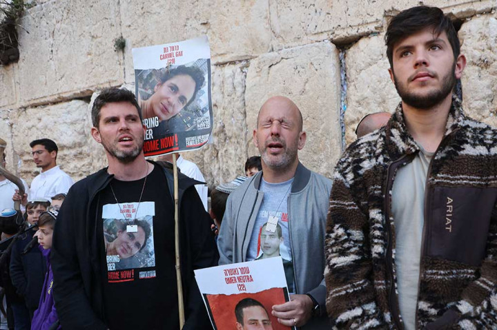 Keluarga para sandera, teman-teman dan pendukungnya, beberapa di antaranya mengenakan kaus bergambar foto mereka, yang merupakan bagian dari kerumunan yang paling dekat dengan tembok.