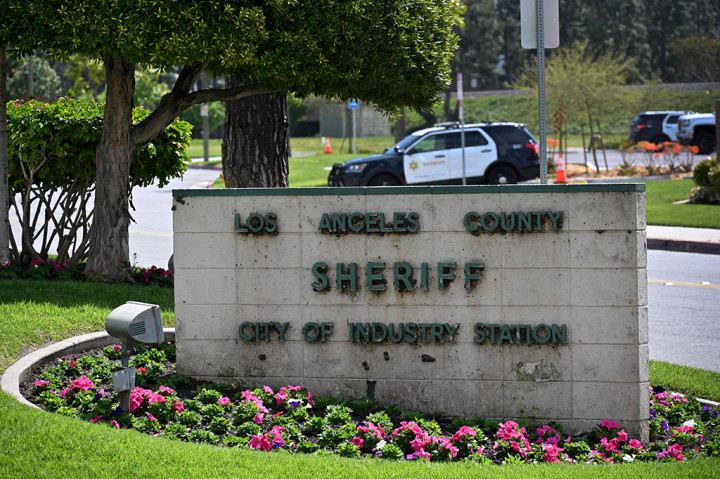 Mobil sheriff terlihat di balik tanda di pintu masuk Stasiun Sheriff Los Angeles County di Kota Industri, California, Senin, 25 Maret 2024 waktu setempat.