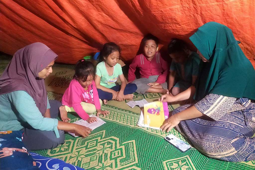 Sementara anak-anak tetap bersemangat belajar meski dengan penerangn seadanya dan tanpa meja kursi di pengungsian di daerah Dusun Air Panas, Desa Kepuh Lagundi, Kecamatan Tambak.