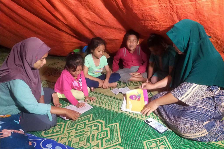 Sementara anak-anak tetap bersemangat belajar meski dengan penerangn seadanya dan tanpa meja kursi di pengungsian di daerah Dusun Air Panas, Desa Kepuh Lagundi, Kecamatan Tambak.