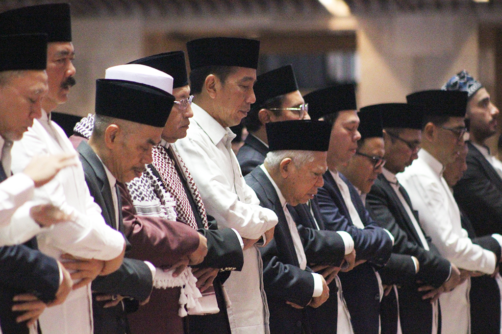 Kepala Negara memakai kemeja putih lengan panjang dengan sarung berwarna hitam. Jokowi bersebelahan dengan Wakil Presiden (Wapres) Ma'ruf Amin dan Imam Besar Masjid Istiqlal Nasaruddin Umar.