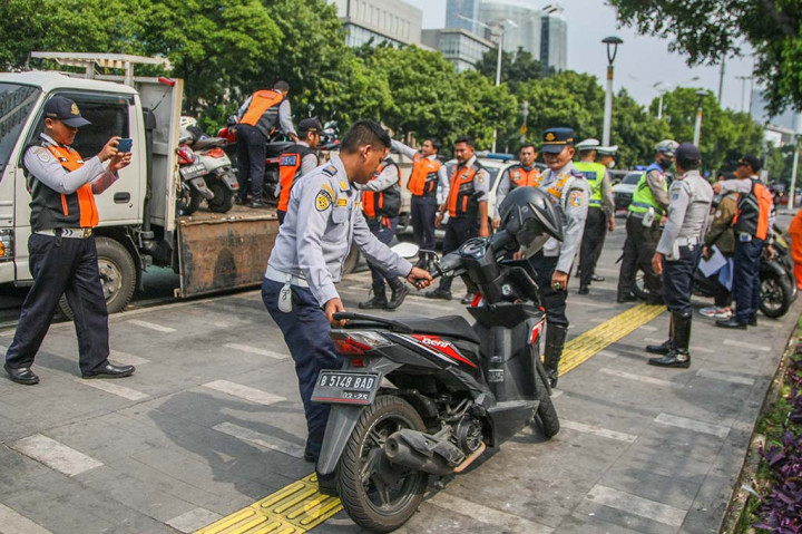 Petugas Dishub mengangkut puluhan sepeda motor yang parkir sembarangan di trotoar Jalan Salemba, Jakarta Pusat, Senin, 6 Mei 2024.
